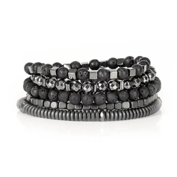 Layered men’s bracelet set featuring black lava stone beads, faceted hematite beads, hematite cube accents, and matte hematite disc beads in a monochromatic stacked design, displayed on a white background.
