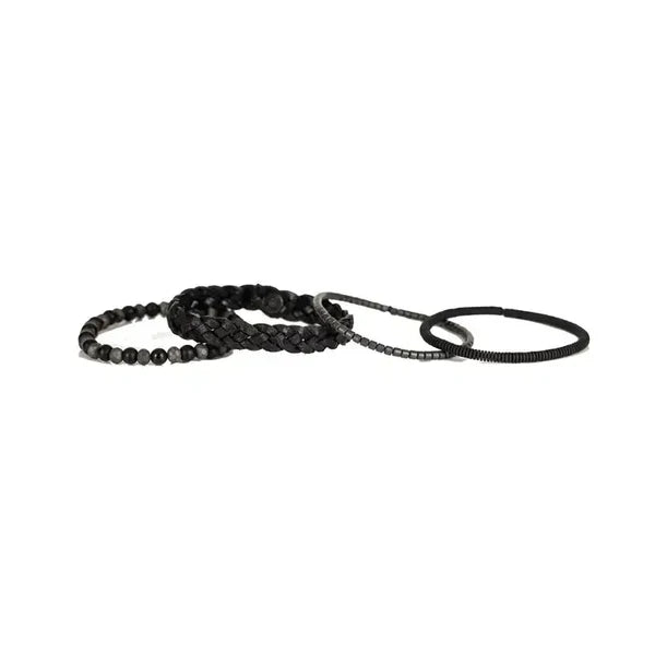 Layered men’s bracelet set featuring a braided black leather band, matte black beads, faceted hematite beads, and hematite disc accents in a monochromatic stacked design, displayed on a white background.
