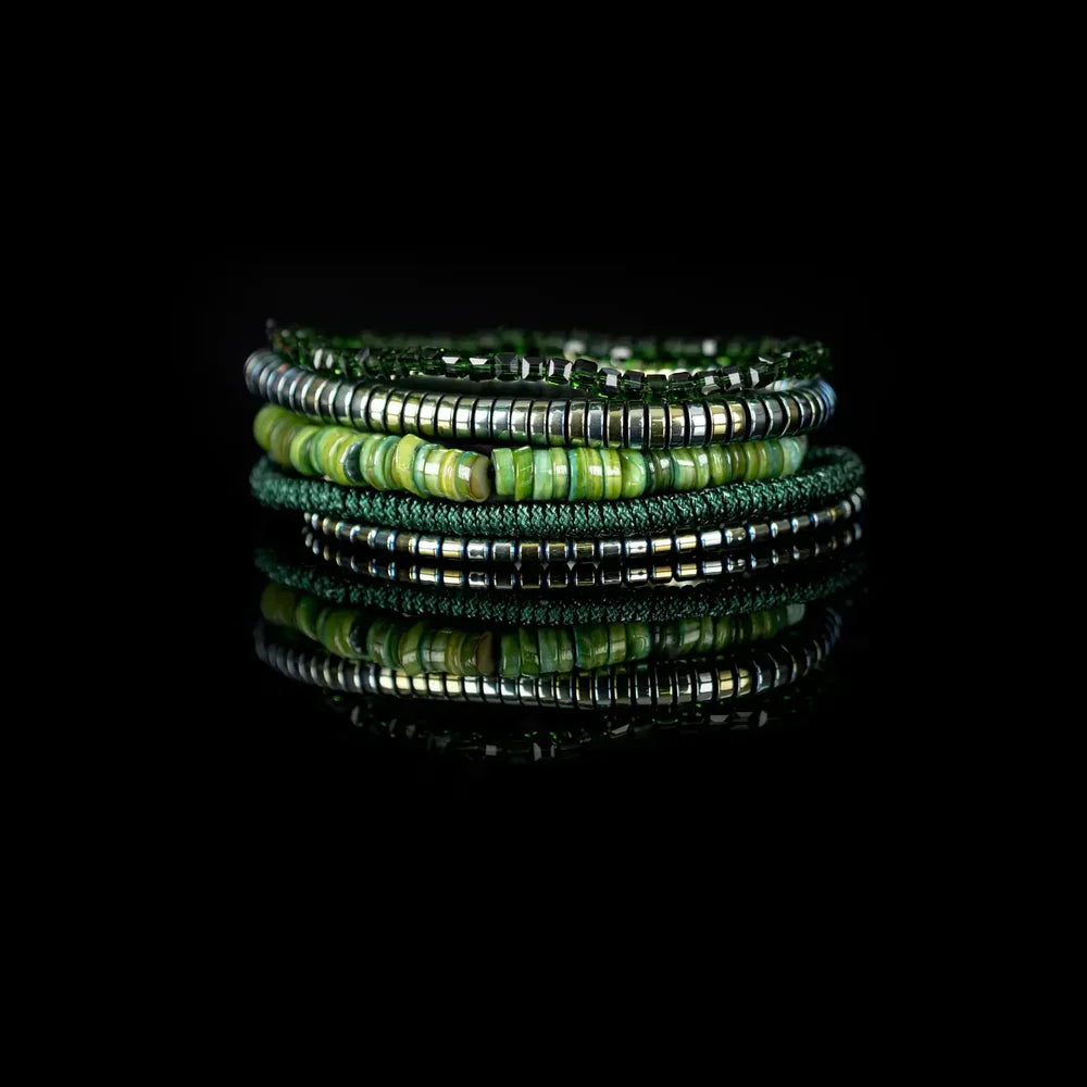 Layered men’s bracelet set featuring green shell heishi beads, metallic hematite beads, faceted dark green crystal beads, and a braided green cord bracelet, displayed on a white background.