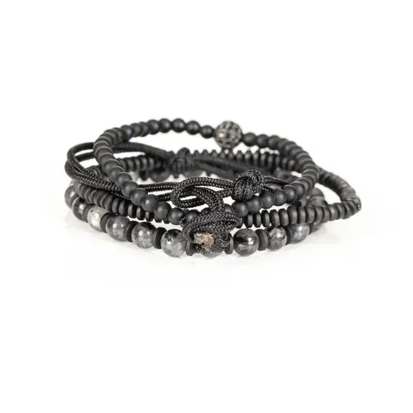 Men's layered black and gray beaded bracelet set featuring matte black beads, natural stone beads, hematite spacers, braided cord strands, and a pavé crystal accent bead in a modern luxury design.