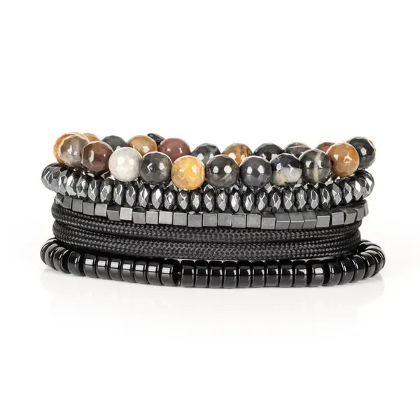 Layered men’s bracelet set featuring multicolor natural stone beads, faceted hematite beads, black hematite cube beads, braided black cord wraps, and glossy black disc beads, displayed on a white background.
