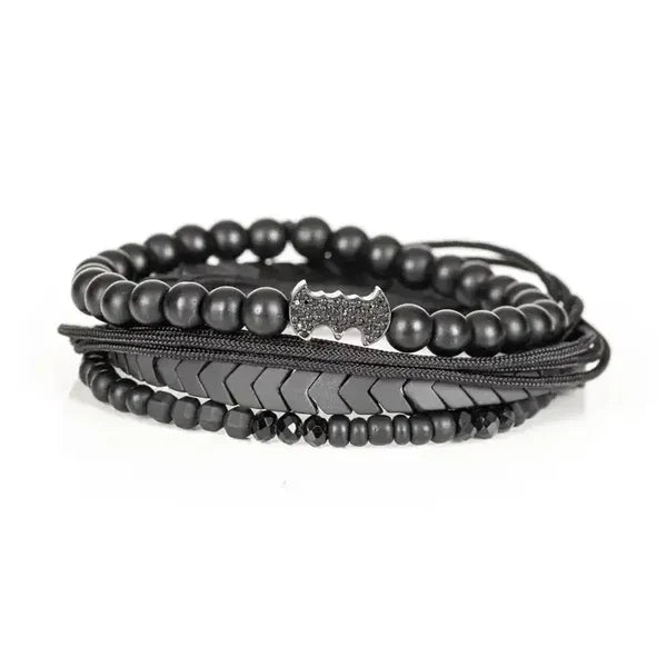 Men's layered black beaded bracelet set featuring matte black beads, hematite arrow-shaped beads, braided cord strands, faceted black crystal accents, and a black pavé bat-shaped centerpiece for a bold modern luxury style.