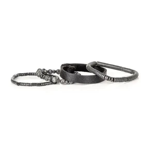 Layered men’s bracelet set featuring a black leather cuff, matte black hematite disc beads, gray natural stone beads, and metallic accent spacers, displayed on a white background.