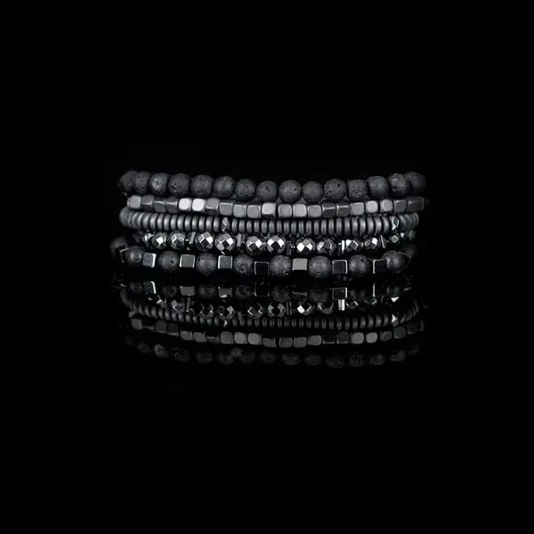 Layered men’s bracelet set featuring black lava stone beads, faceted hematite beads, hematite cube accents, and matte hematite disc beads in a monochromatic stacked design, displayed on a white background.