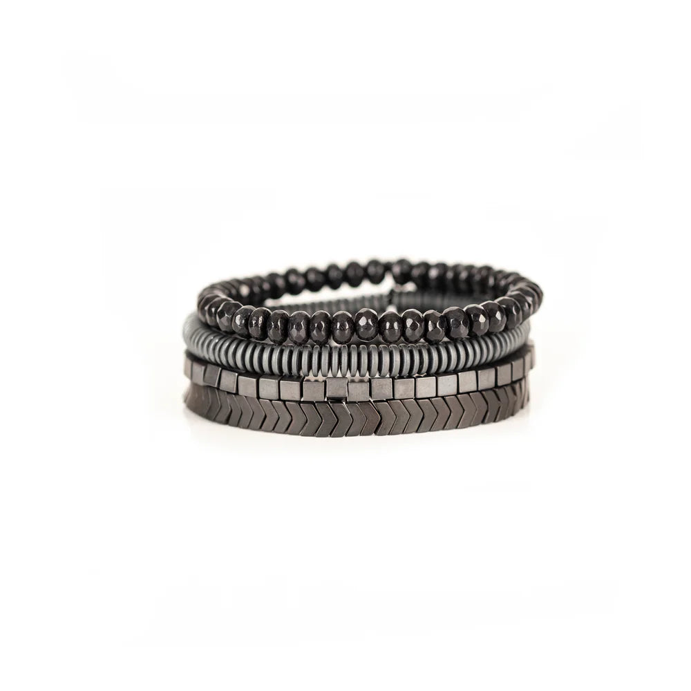 Men's handcrafted layered bracelet set featuring faceted black hematite beads, matte gray heishi disc beads, polished hematite cube beads, and black hematite arrow-shaped beads. Premium minimalist men's bracelet stack photographed on a clean white background.