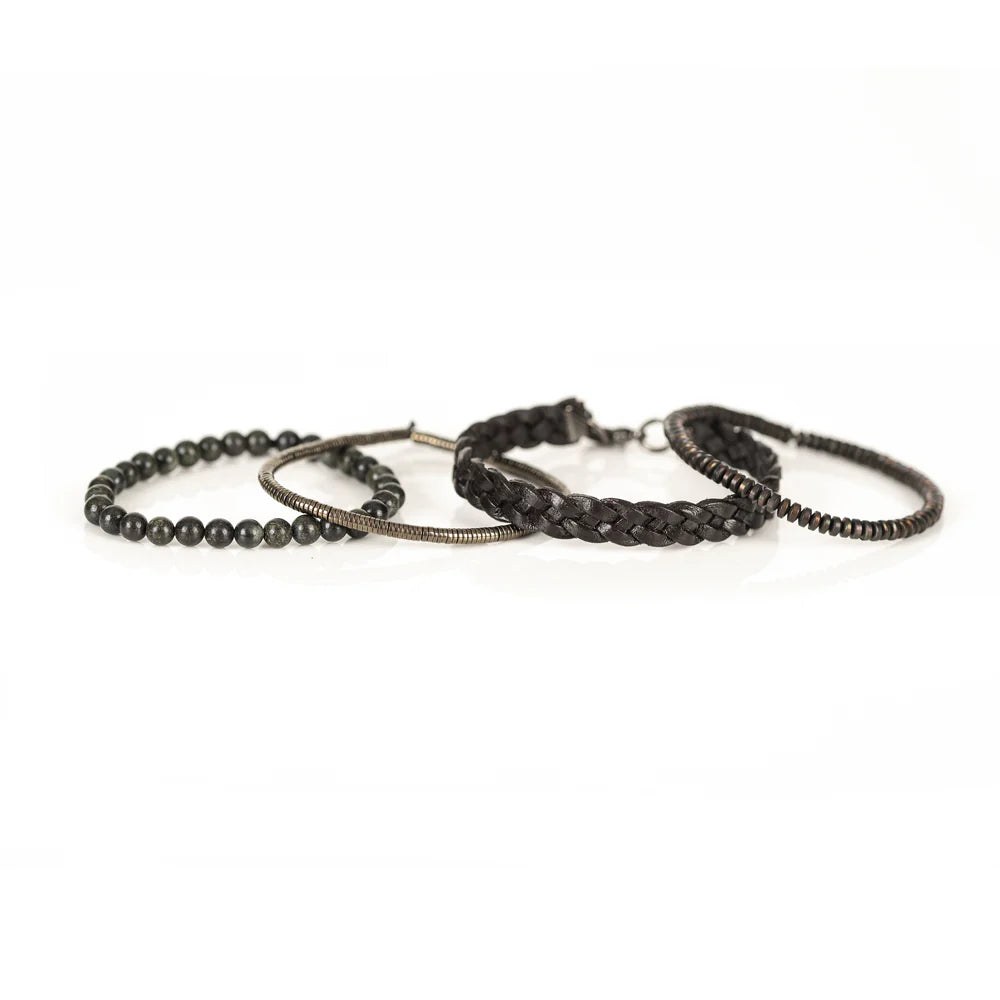 Men's handcrafted layered bracelet set featuring a dark brown braided genuine leather bracelet, natural green serpentine gemstone beads, bronze hematite heishi beads, and metallic spacer beads. Premium artisan men's bracelet stack photographed on a clean white background.