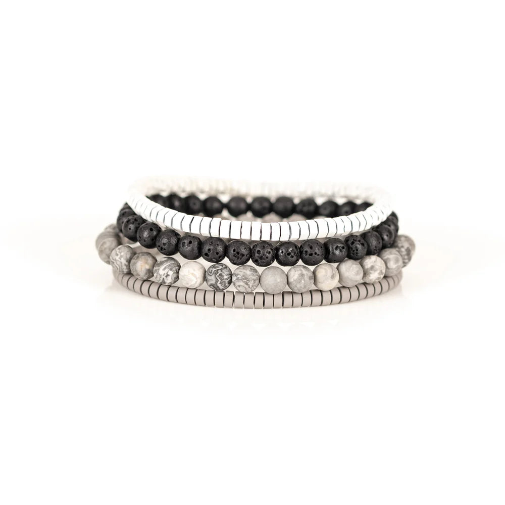 Men's handcrafted layered bracelet set featuring white heishi disc beads, black lava stone beads, natural white and gray jasper gemstone beads, and matte silver hematite heishi spacers. Premium minimalist men's bracelet stack photographed on a clean white background.