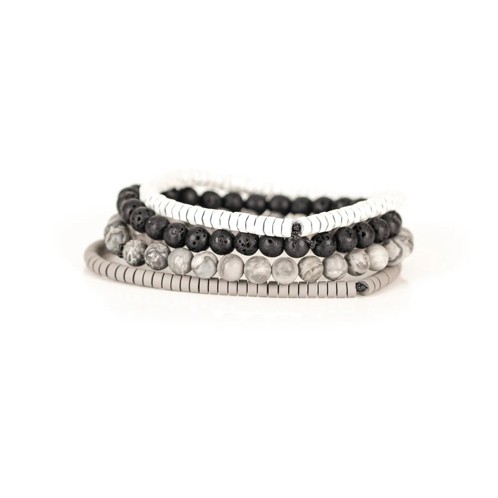 Men's handcrafted layered bracelet set featuring white heishi disc beads, black lava stone beads, natural white and gray jasper gemstone beads, and matte silver hematite heishi spacers. Premium minimalist men's bracelet stack photographed on a clean white background.