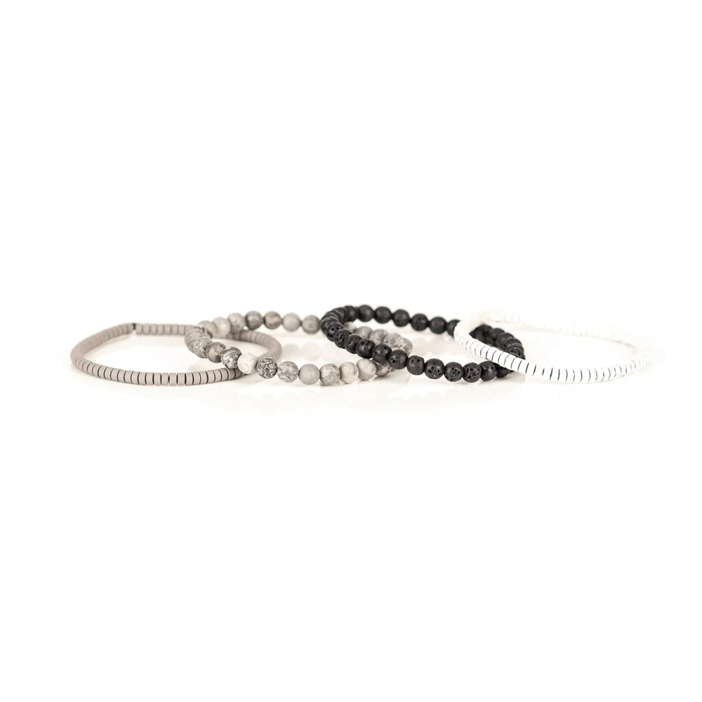 Men's handcrafted layered bracelet set featuring white heishi disc beads, black lava stone beads, natural white and gray jasper gemstone beads, and matte silver hematite heishi spacers. Premium minimalist men's bracelet stack photographed on a clean white background.