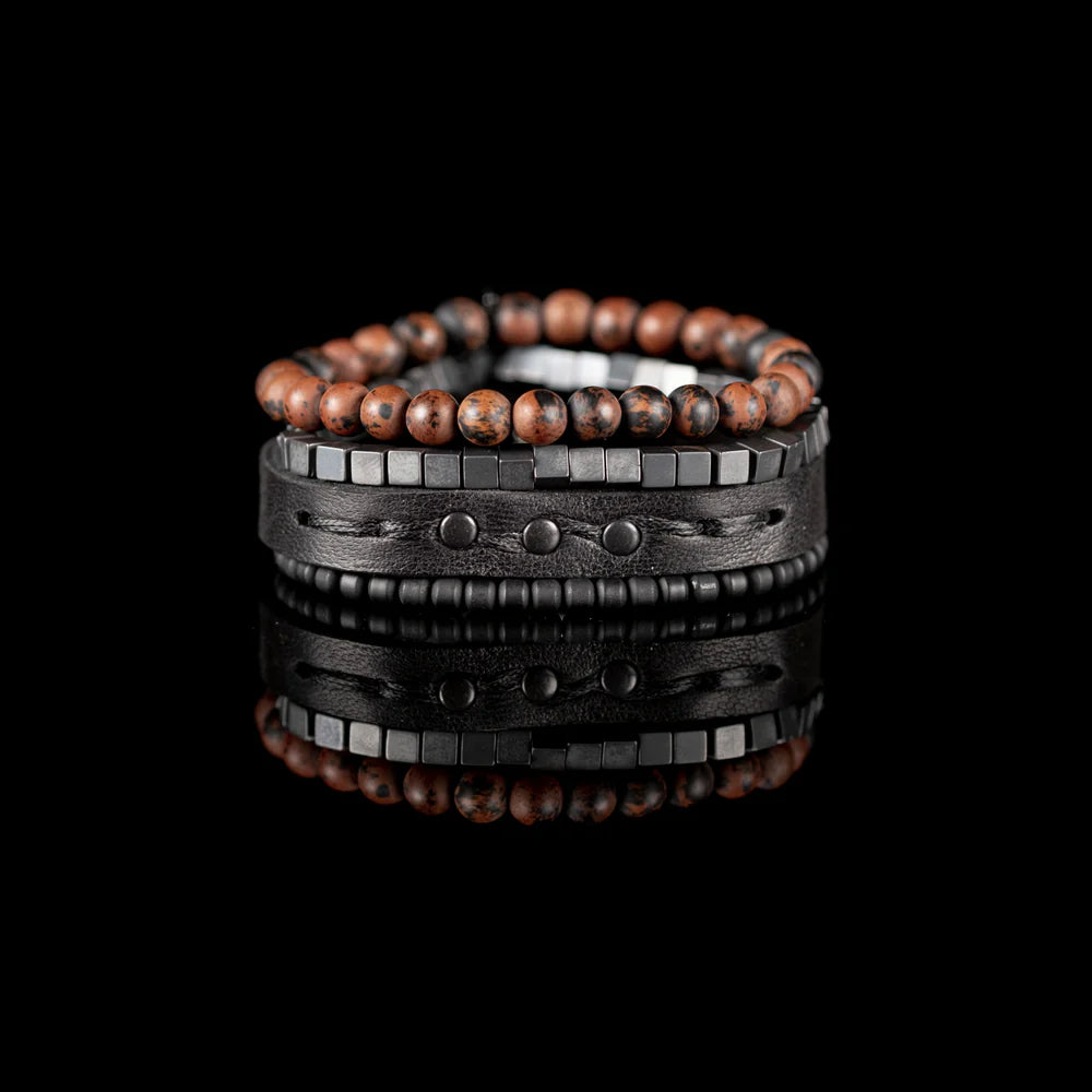 Men's handcrafted black leather wrap bracelet set featuring brown mahogany obsidian gemstone beads, matte black hematite cube beads, black seed beads, and a premium layered leather cuff with stitched detailing. Luxury men's bracelet stack photographed on a clean white background.