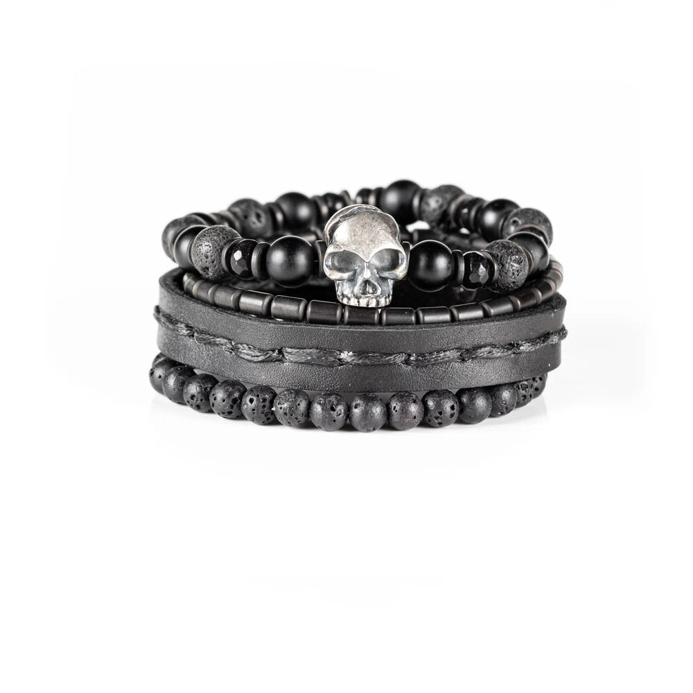Men's handcrafted black leather wrap bracelet set featuring matte black onyx beads, natural lava stone beads, hematite accents, and a silver skull centerpiece. Premium layered men's bracelet stack photographed on a clean white background.