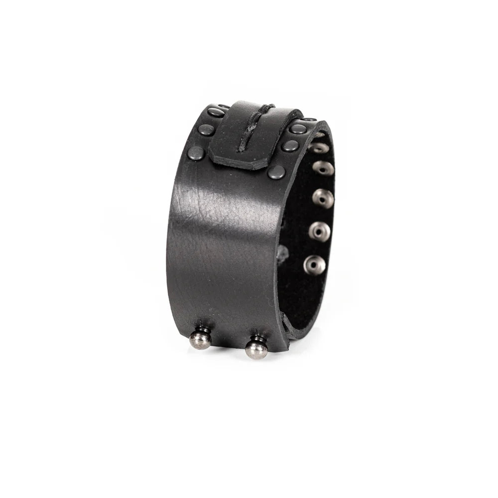Black genuine leather cuff bracelet with hand-stitched center strap and black metal stud detailing, handcrafted statement accessory on a white background.