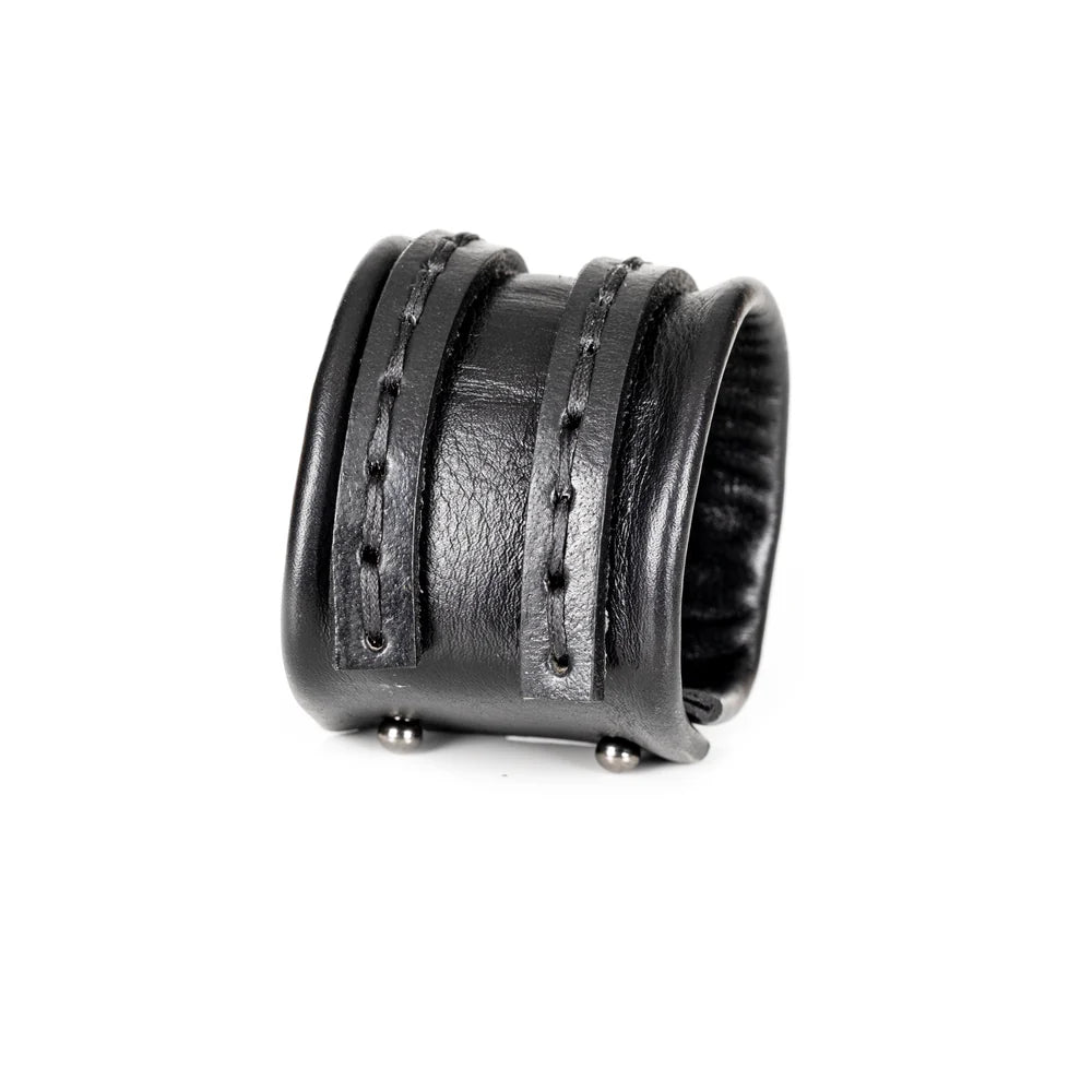 Black genuine leather cuff bracelet with a wide padded center band and hand-stitched wrap straps, handcrafted minimalist statement accessory on a white background.