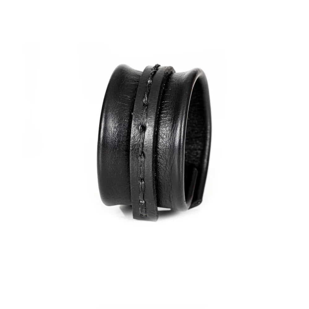 Black genuine leather cuff bracelet with a sculpted padded design, hand-stitched wrap strap detail, and handcrafted artisan finish on a white background.