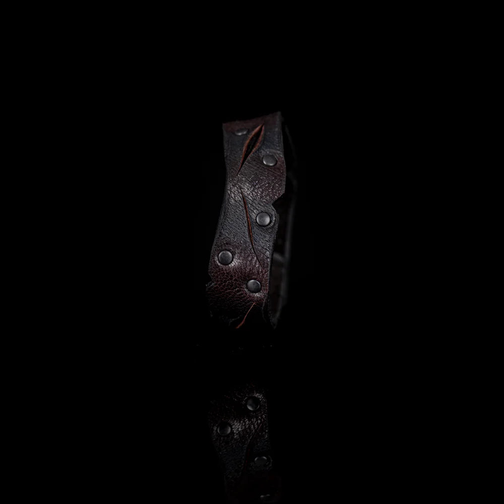 Black genuine leather cuff bracelet with sculpted wave-cut edges, black rivet detailing, and a handcrafted artisan finish, displayed on a white background.