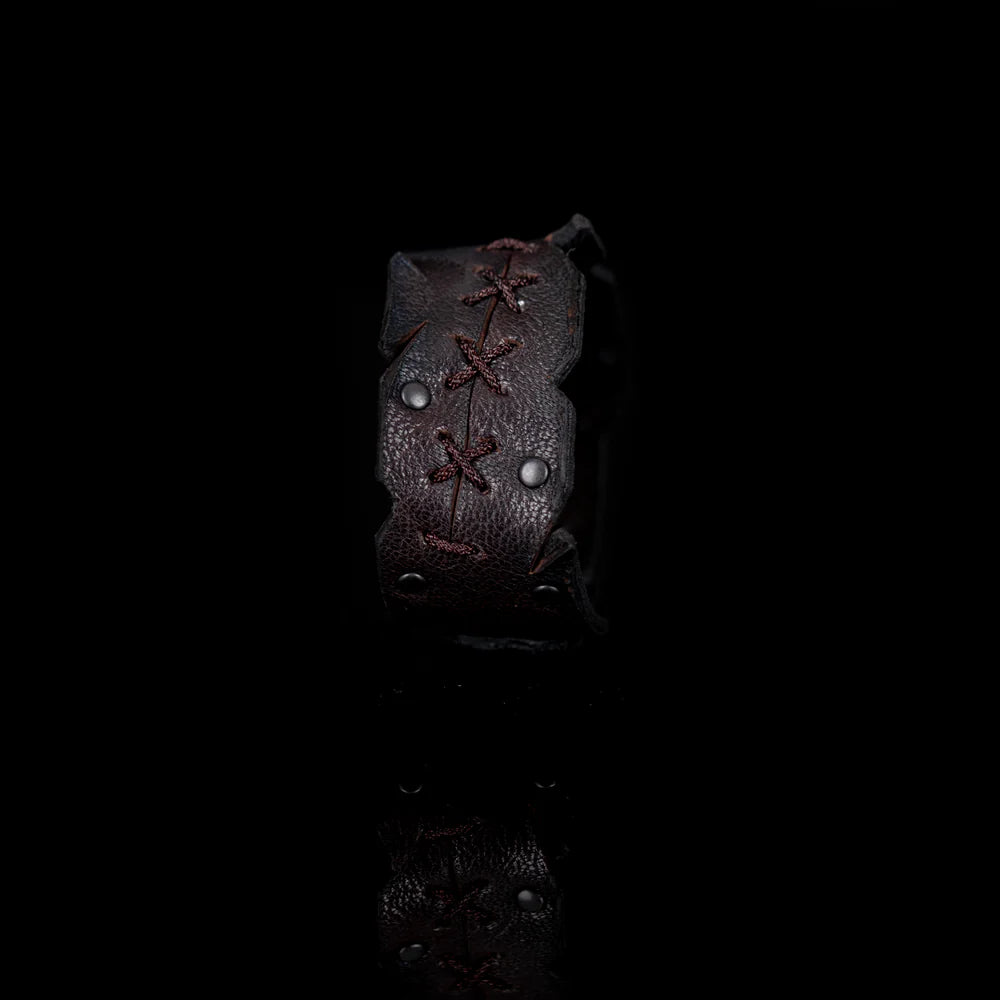Black genuine leather cuff bracelet with hand-laced stitching, raw cut edges, and black rivet accents, handcrafted artisan statement accessory on a white background.