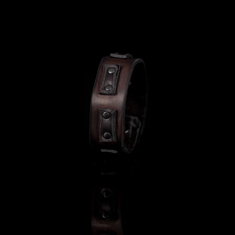Men's handcrafted genuine leather cuff bracelet in dark brown featuring a wide minimalist design with black leather accent panels, matte black rivet hardware, and premium artisan craftsmanship. Luxury men's leather wristband photographed on a clean white background.
