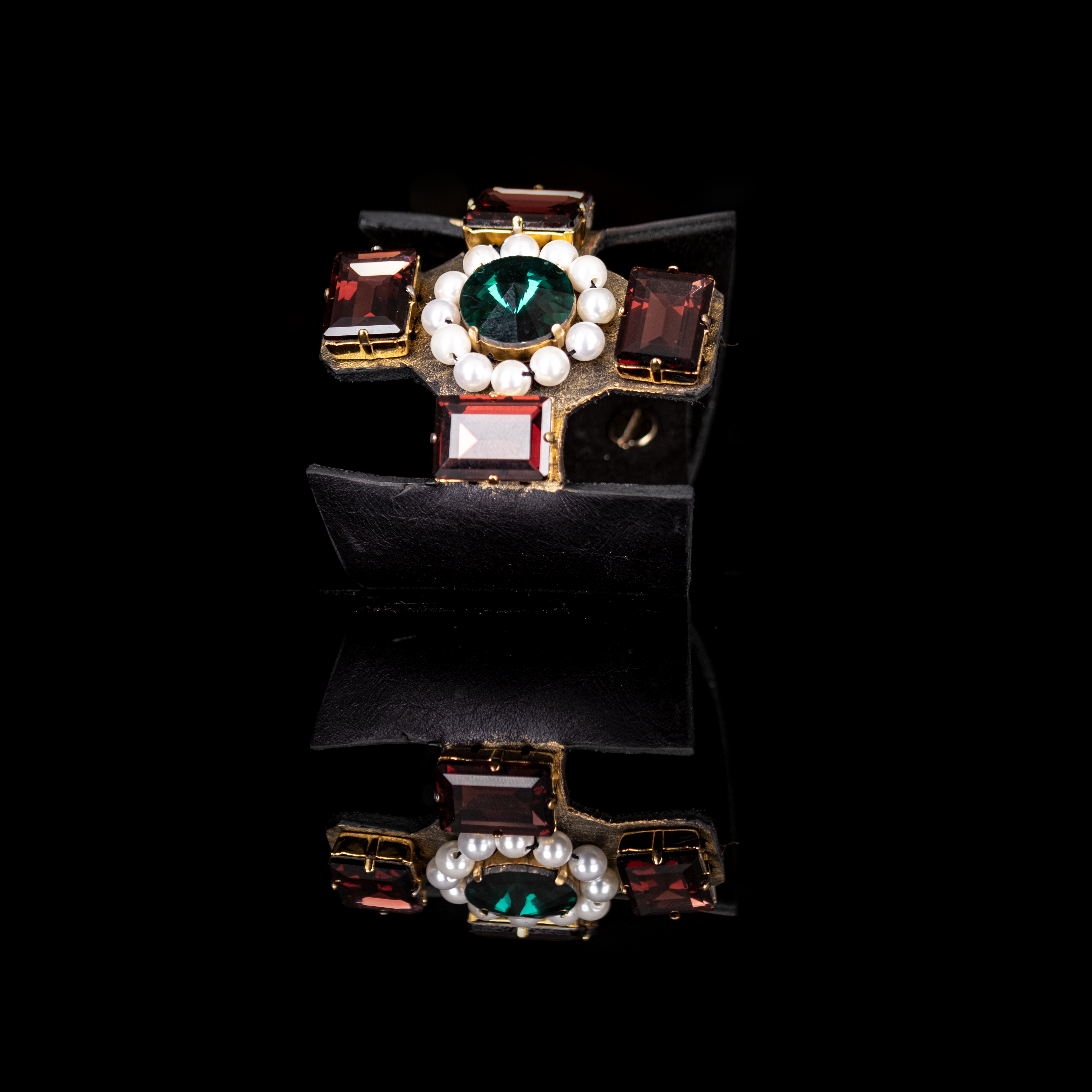 Black leather cuff with emerald green center stone, red crystals, and pearl detailing, statement bracelet