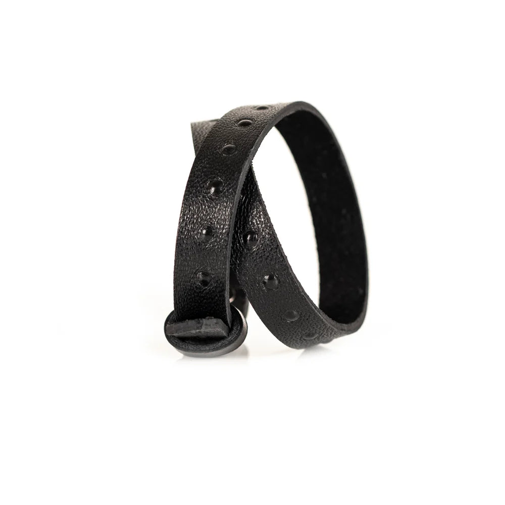 Black genuine leather wrap bracelet with embossed stud detailing and an adjustable strap closure, handcrafted minimalist accessory on a white background.