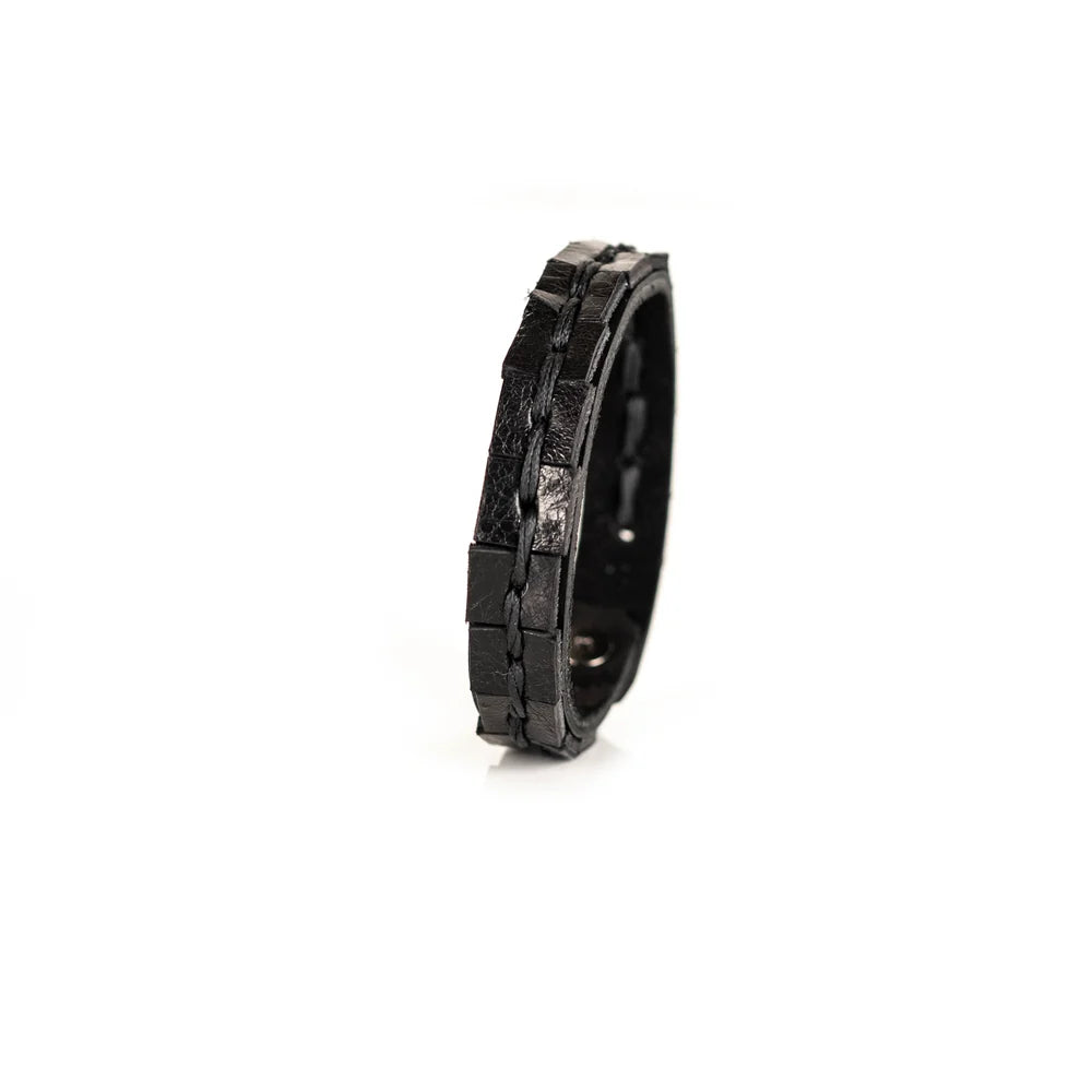 Black genuine leather bracelet featuring a hand-stitched center detail and geometric cut leather accents, handcrafted artisan accessory on a white background.
