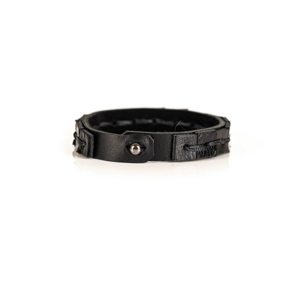 Black genuine leather bracelet featuring a hand-stitched center detail and geometric cut leather accents, handcrafted artisan accessory on a white background.