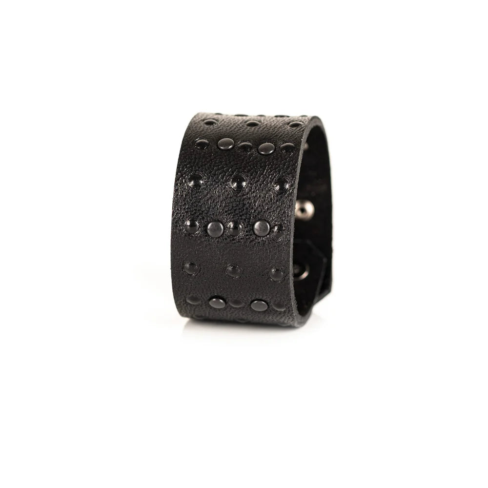Black genuine leather cuff bracelet with black stud detailing arranged in a geometric pattern, handcrafted statement accessory with a textured leather finish on a white background.