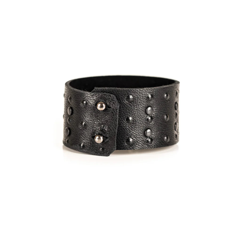 Black genuine leather cuff bracelet with black stud detailing arranged in a geometric pattern, handcrafted statement accessory with a textured leather finish on a white background.