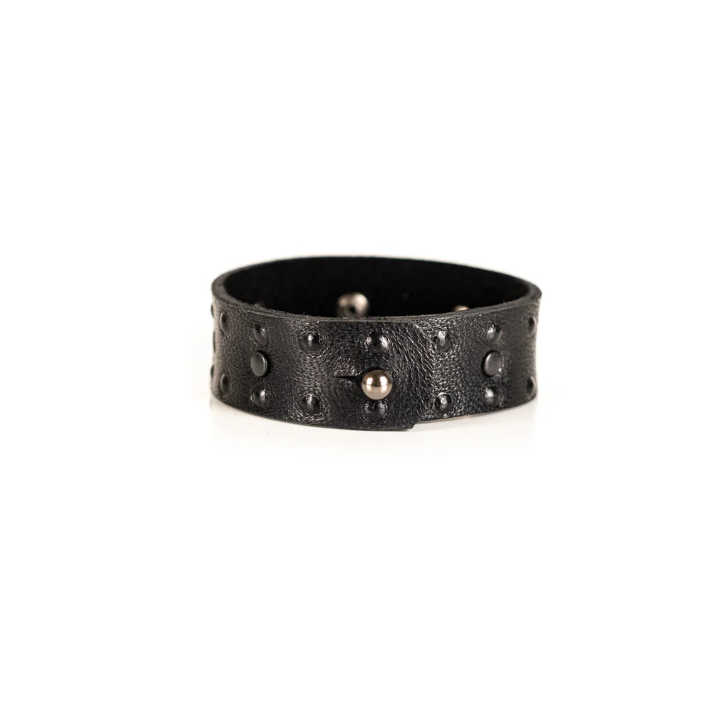 Black genuine leather cuff bracelet with black stud accents and textured leather finish, handcrafted minimalist statement accessory on a white background.