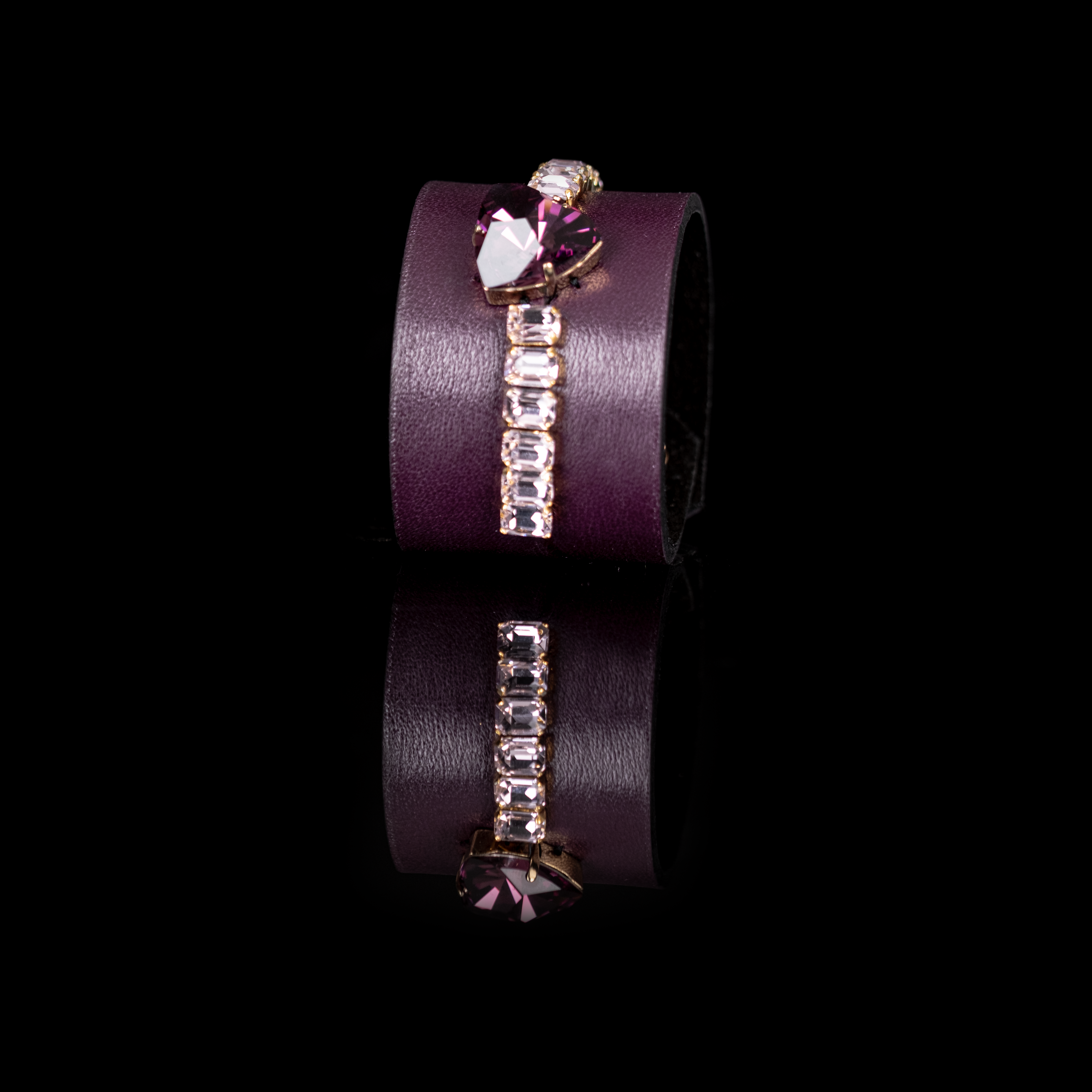 Burgundy leather cuff bracelet with large purple crystal and clear rectangular rhinestone row, wide statement bracelet on white background