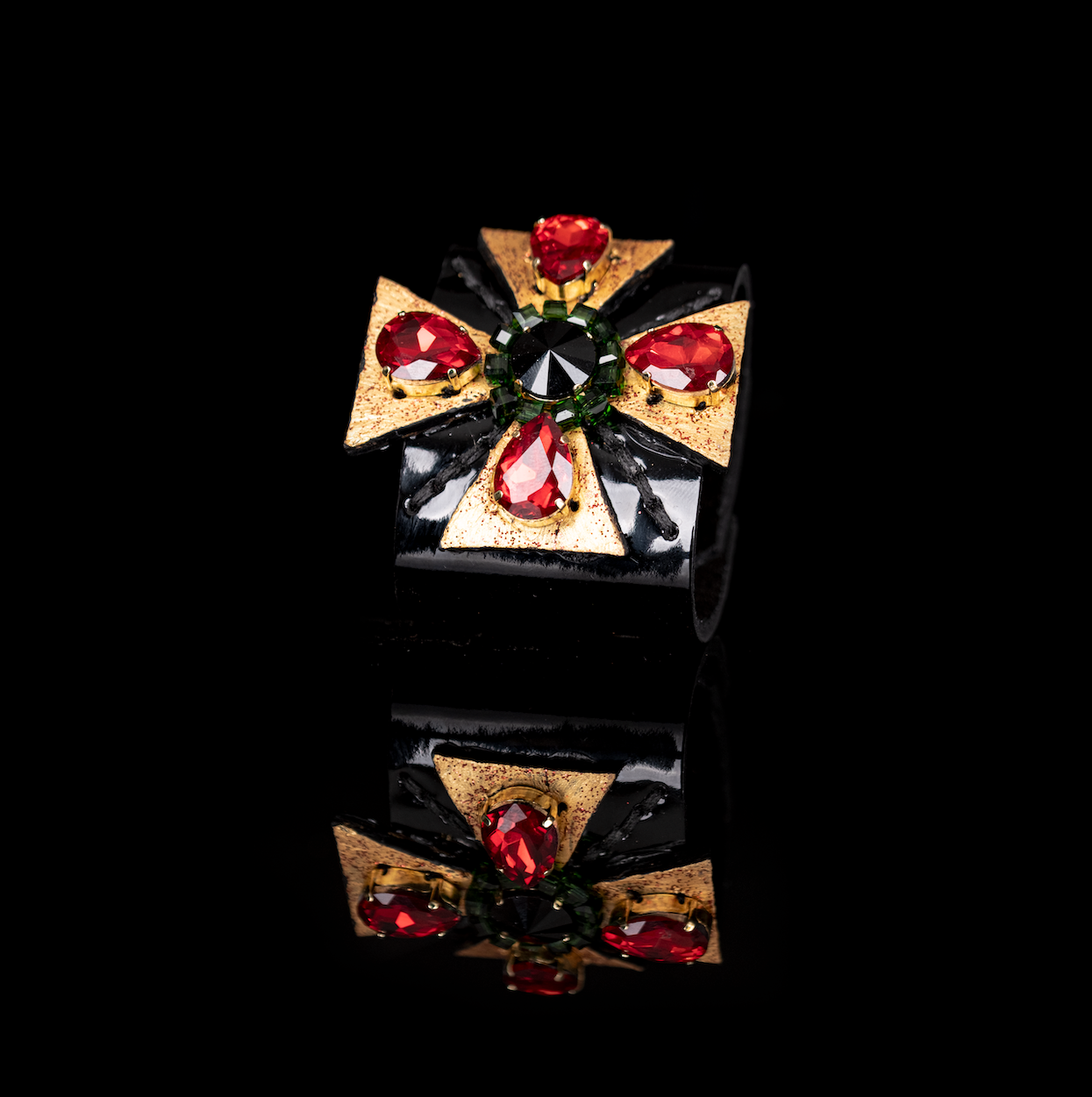 Black leather cuff bracelet with red teardrop crystals and central black stone, gold geometric star design statement bracelet for women