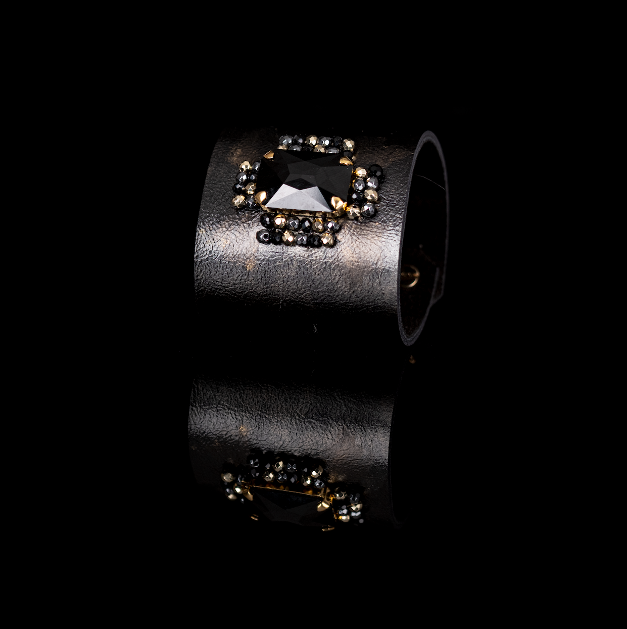 Black leather cuff bracelet with large black crystal centerpiece and gold bead details, handmade statement bracelet by THE DARK