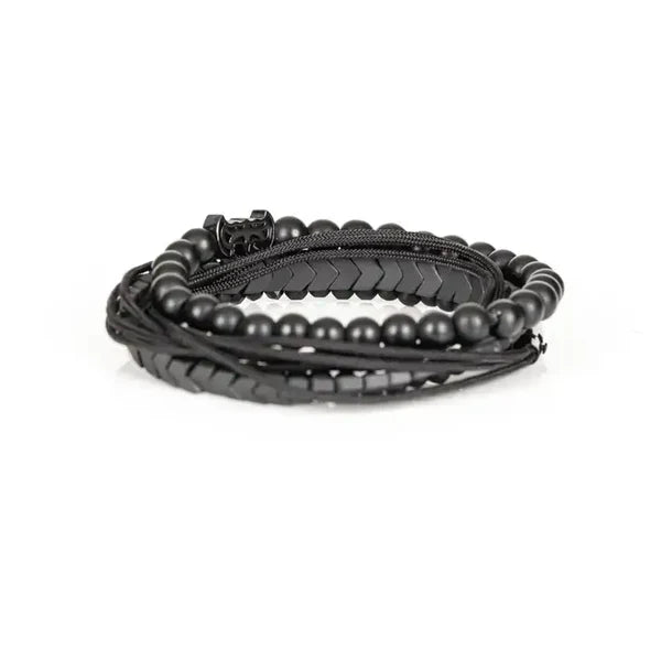 Men's layered black beaded bracelet set featuring matte black beads, hematite arrow-shaped beads, braided cord strands, faceted black crystal accents, and a black pavé bat-shaped centerpiece for a bold modern luxury style.