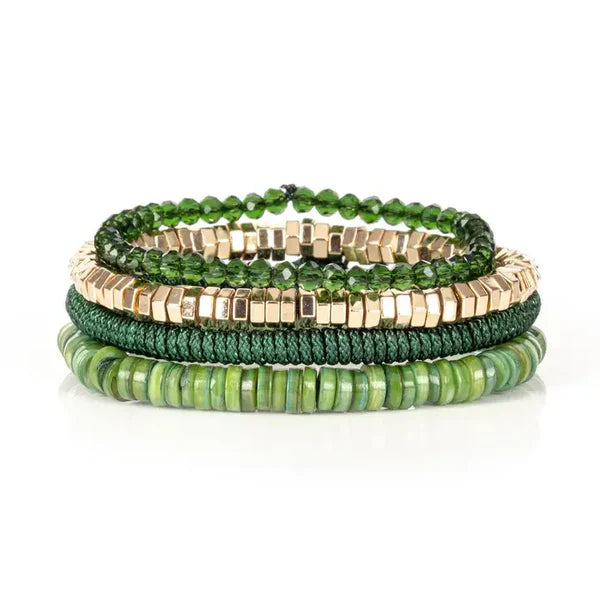 Layered men’s bracelet set featuring green shell heishi beads, faceted dark green crystal beads, gold-tone hematite cube beads, and a braided green cord bracelet, displayed on a white background.
