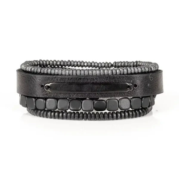Layered men’s bracelet set featuring a black leather band with a black metal plate, matte hematite cube beads, and hematite disc beads in a sleek monochromatic design, displayed on a white background.