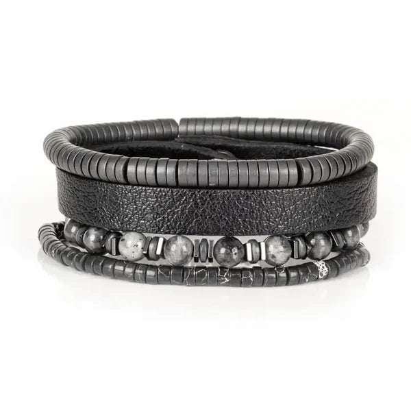Layered men’s bracelet set featuring a black leather cuff, matte black hematite disc beads, gray natural stone beads, and metallic accent spacers, displayed on a white background.