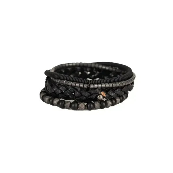 Layered men’s bracelet set featuring a braided black leather band, matte black beads, faceted hematite beads, and hematite disc accents in a monochromatic stacked design, displayed on a white background.