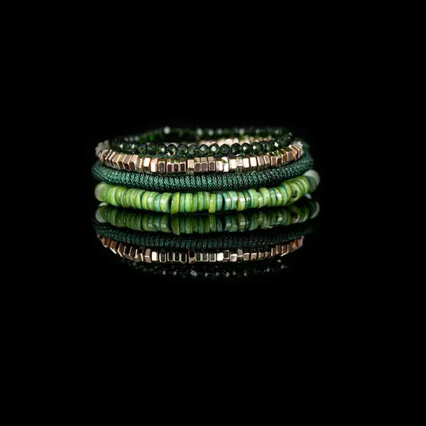 Layered men’s bracelet set featuring green shell heishi beads, faceted dark green crystal beads, gold-tone hematite cube beads, and a braided green cord bracelet, displayed on a white background.