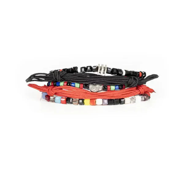 Layered men’s bracelet set featuring black and coral braided cord bracelets, multicolor bead accents, black faceted beads, and a silver-tone skull centerpiece, displayed on a white background.
