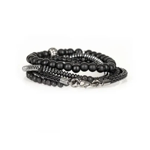 Black layered men’s bracelet with lava stone beads, braided leather detail, silver-tone accents, and crystal pavé centerpiece on a white background.