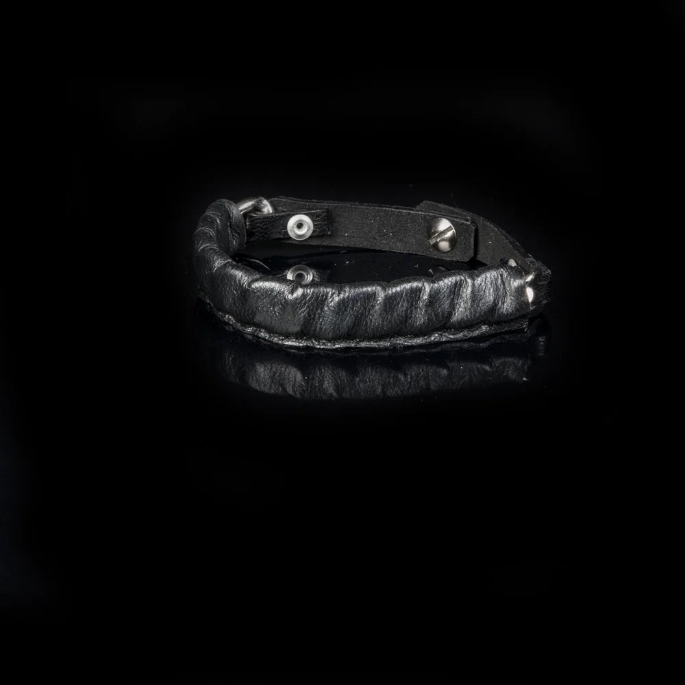 Men's black leather wrap bracelet featuring a padded stitched band, adjustable leather strap, and silver-tone hardware for a rugged modern look.