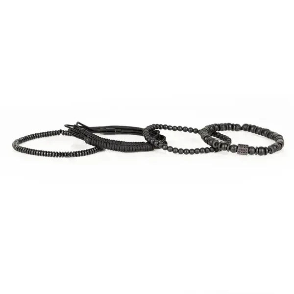 Men's layered black bracelet set featuring matte black beads, lava stone beads, hematite spacers, braided cord strands, and a black pavé cubic zirconia square centerpiece in a sleek modern luxury design.