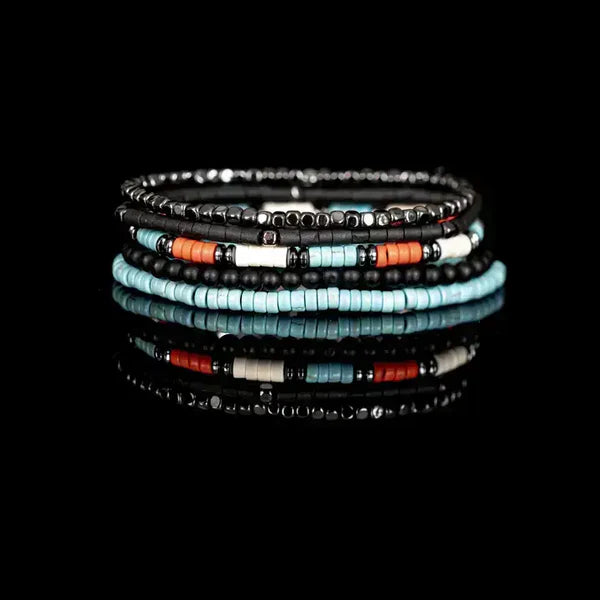 Layered men’s bracelet set featuring turquoise heishi beads, black matte beads, orange accent beads, and silver-tone hematite beads on elastic strands, displayed on a white background