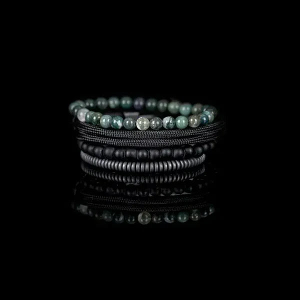 Layered men’s bracelet set featuring green natural stone beads, black matte beads, braided black cord wraps, and matte hematite disc beads, displayed on a white background.