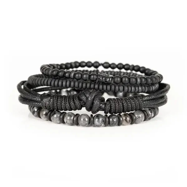 Men's layered black bracelet set featuring matte black beads, natural gray stone beads, braided leather cords, black wood beads, and hematite spacers in a rugged contemporary luxury design.