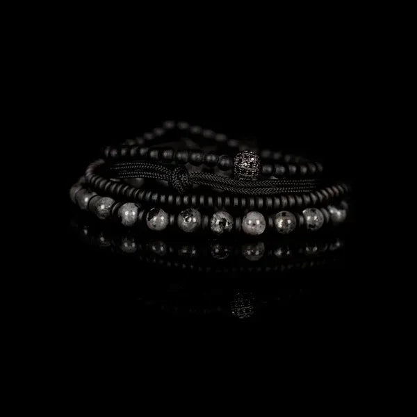 Men's layered black and gray beaded bracelet set featuring matte black beads, natural stone beads, hematite spacers, braided cord strands, and a pavé crystal accent bead in a modern luxury design.