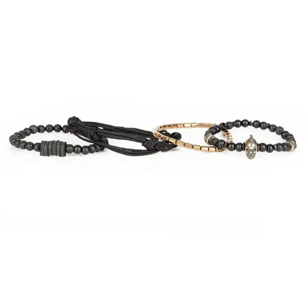 Black layered men’s bracelet with matte black beads, lava stone accents, braided cord wraps, bronze-tone metal beads, and a Spartan skull centerpiece on a white background.