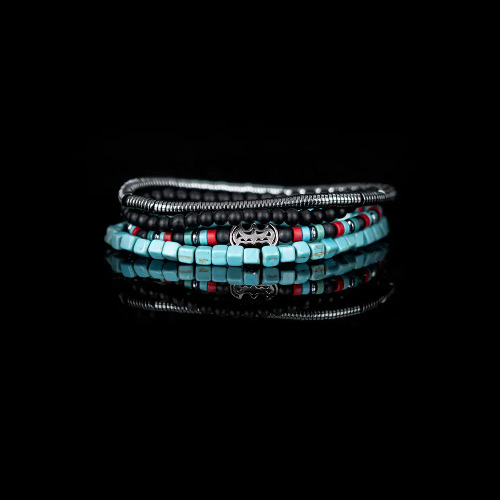 Layered men’s bracelet set featuring turquoise cube beads, black matte stone beads, silver-tone hematite beads, colorful accent beads, and a crystal pavé bat centerpiece, displayed on a white background.