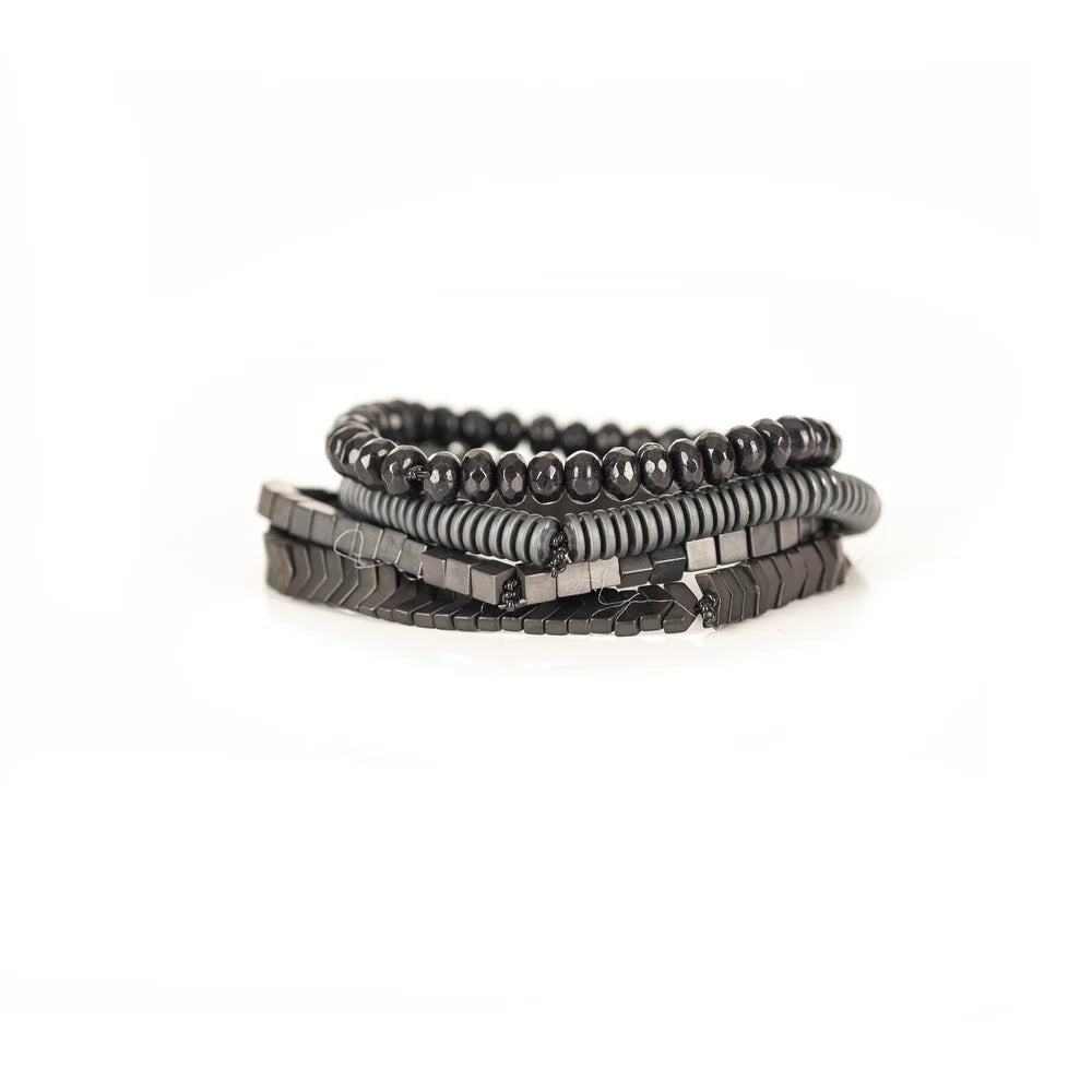 Men's handcrafted layered bracelet set featuring faceted black hematite beads, matte gray heishi disc beads, polished hematite cube beads, and black hematite arrow-shaped beads. Premium minimalist men's bracelet stack photographed on a clean white background.