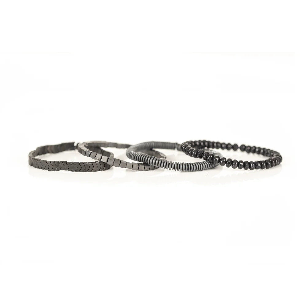 Men's handcrafted layered bracelet set featuring faceted black hematite beads, matte gray heishi disc beads, polished hematite cube beads, and black hematite arrow-shaped beads. Premium minimalist men's bracelet stack photographed on a clean white background.