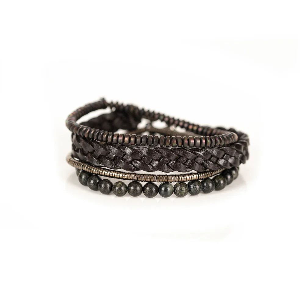Men's handcrafted layered bracelet set featuring a dark brown braided genuine leather bracelet, natural green serpentine gemstone beads, bronze hematite heishi beads, and metallic spacer beads. Premium artisan men's bracelet stack photographed on a clean white background.